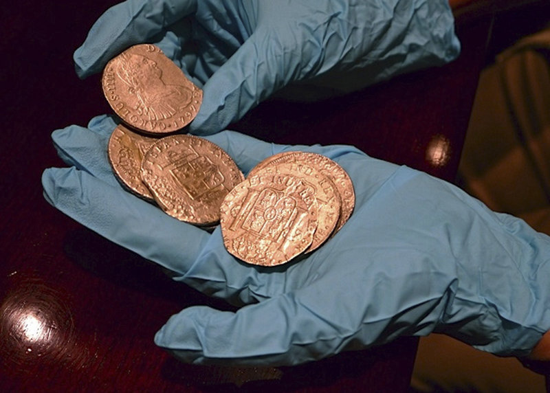 A member of Spain’s Culture Ministry technical crew displays some of the 594,000 coins from the Nuestra Senora de las Mercedes.