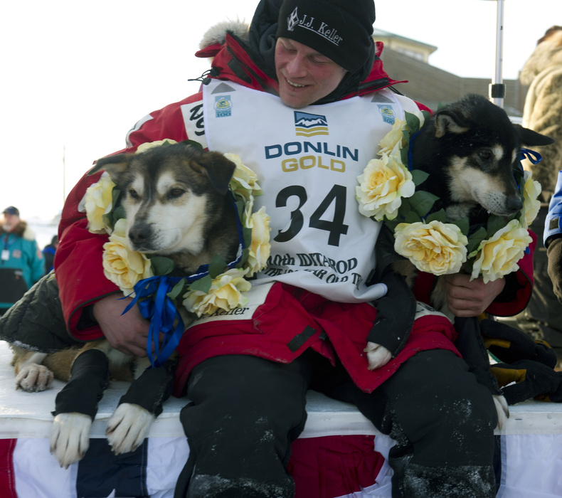 Dallas Seavey holds his leaders, Diesel, left, and Guiness after he arrived at the finish line to claim victory in the Iditarod Trail Sled Dog Race in Nome, Alaska, on Tuesday.