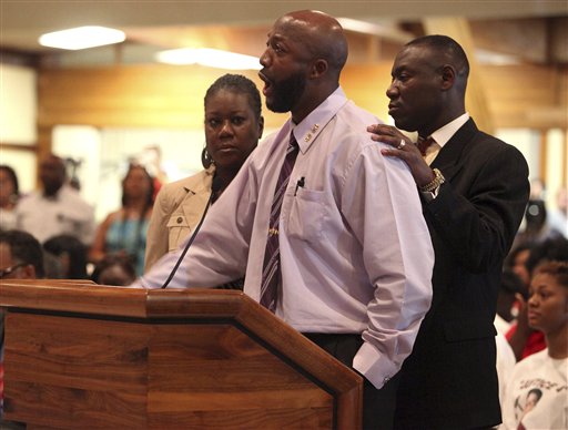 Tracy Martin, center, speaks at the Sanford City Commission meeting with Trayvon's mother, Sybrina Fulton, left, and the family lawyer, Benjamin Crump at the Sanford Civic Center in Sanford Fla., Monday.