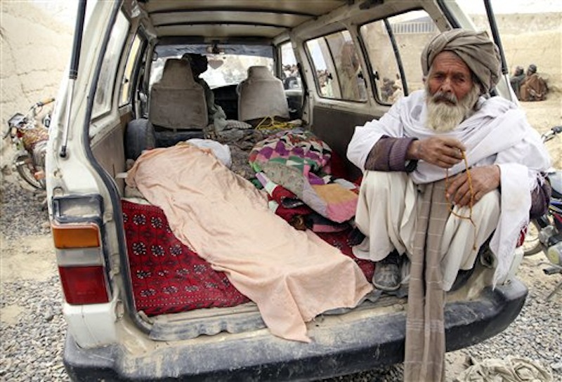 An elderly Afghan man sits next to the covered body of a person who was allegedly killed by a U.S. service member, in a minibus in Panjwai, Kandahar province south of Kabul, Afghanistan on Sunday, March 11, 2012. A U.S. service member walked out of a base in southern Afghanistan before dawn Sunday and started shooting Afghan civilians, according to villagers and Afghan and NATO officials. Villagers showed an Associated Press photographer 15 bodies, including women and children, and alleged they were killed by the American. (AP Photo/Allauddin Khan)