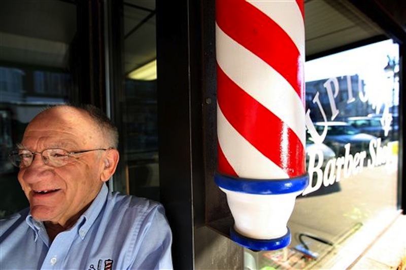 In this March 5, 2010 photo Howard Rettenmeier, who has cut hair for 55 years at the Uptown Barber Shop, stands by the barber pole at his Dyersville, Iowa, shop. The barber pole, one of the oldest signs that can be seen on storefronts across America, is an increasing source of friction between barbers and beauticians over which businesses get to display the iconic striped poles. (AP Photo/The Telegraph Herald, Dave Kettering)