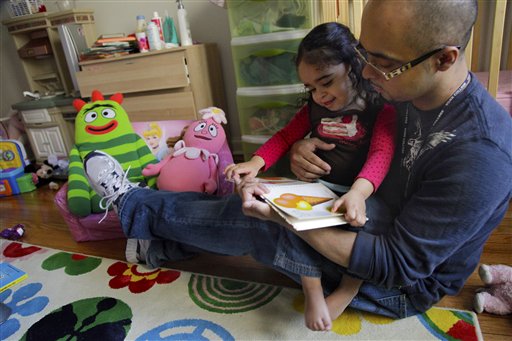 Christopher Astacio reads with his daughter Cristina, 2, who was recently diagnosed with a mild form of autism.