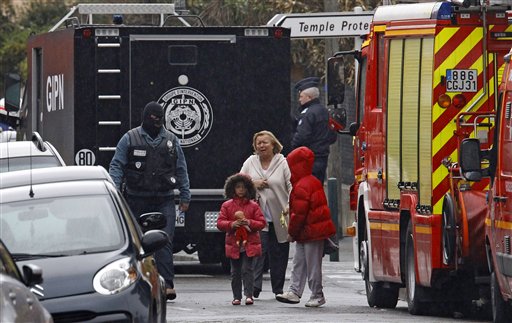 A woman and children are escorted by a police officer near a building where the chief suspect in an al-Qaida-linked killing spree is holed up in an apartment in Toulouse, France, today.