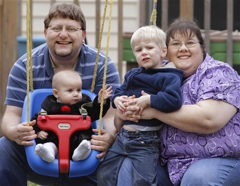 In this photo, Nathen and Melissa Cobb pose with their two children Joshua, 3, and Savannah, 7 months, at their home in Riverton, Ill. The Cobbs tried to refinance their home last year and didn't qualify for the loan because of medical bills that had been sent to a collection agency. They were surprised because the bills had been paid. They now know that the collection action can stay on their credit report for seven years. (AP Photo/Seth Perlman)