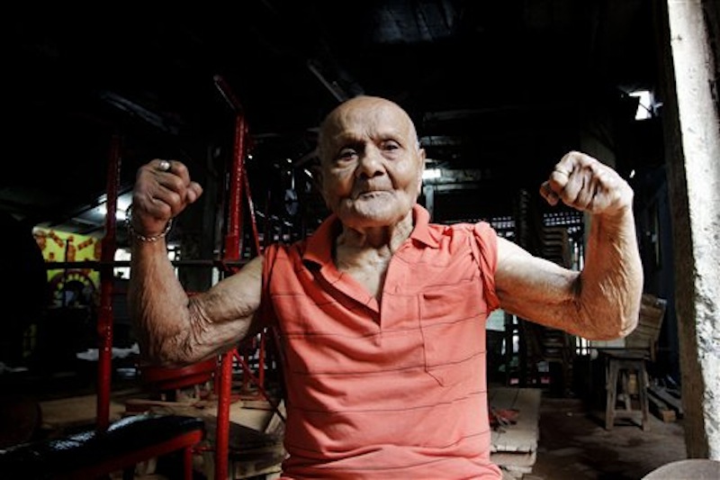 In this Friday, March 16, 2012 photo, Indian body builder Manohar Aich flexes his muscles as he poses for a photograph in a gymnasium in Kolkata, India. Aich, who is only 4 foot 11 inches (150 centimeters) tall, won the Mr. Universe title in London way back in 1952. Happiness and a life without tensions are the key to his longevity, said Aich, who turned 100 on March 17. (AP Photo/Bikas Das)