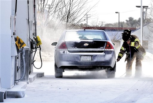 Skowhegan Fire Department Capt. Rick Caldwell wears protective gear while using an air hose to blow off fire suppressant powder that covered vehicles, customers and the ground at the Irving Circle K store. At least one person was sent to the hospital and several were examined.