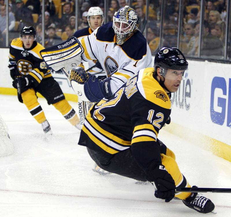 Brian Rolston (12) goes after the puck in front of Buffalo Sabres goalie Jhonas Enrothin (1) behind the net Thursday in Boston. The Bruins won, 3-1.