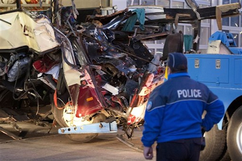 A police officer works at the wreckage of a tourist bus from Belgium at the accident site in a tunnel of the A9 highway near Sierre, western Switzerland, early Wednesday, March 14, 2012. A bus carrying Belgian students returning from a ski holiday crashed into a wall in a Swiss tunnel, killing 22 Belgian 12-year-olds and six adults, police said Wednesday. (AP Photo/Keystone, Laurent Gillieron)