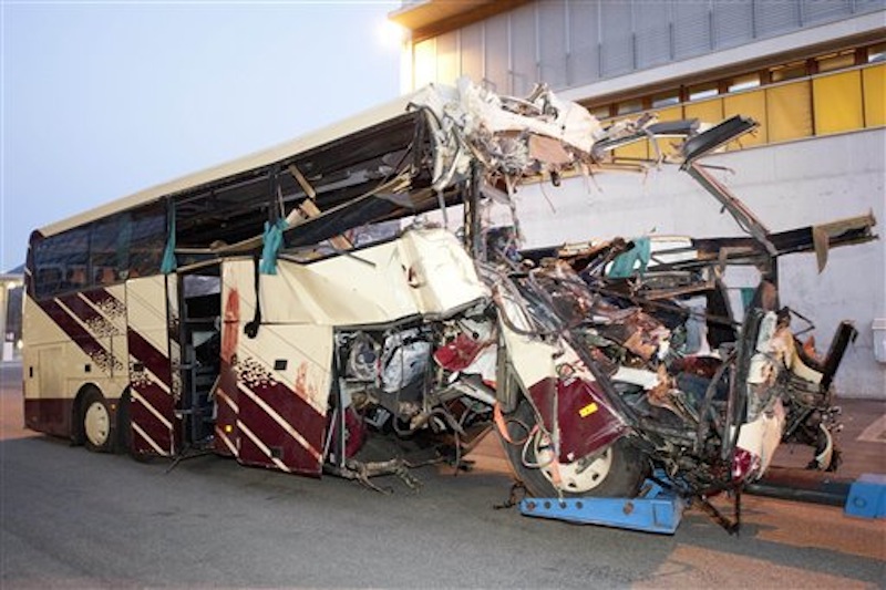 The wreckage of a tourist bus from Belgium is dragged by a tow truck outside the tunnel of the motorway A9, in Sierre, western Switzerland, early Wednesday, March 14, 2012. 28 people were killed in the bus crash. (AP Photo/Keystone, Laurent Gillieron)