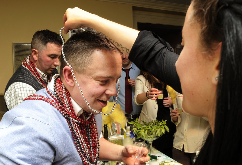 Adrian Trudeau, a bartender at Academe in Kennebunk, receives a set of beads from a voter at Maine Restaurant Week’s Signature Event at the Portland Harbor Hotel Wednesday evening. His cocktail contained basil and cucumber vodka.