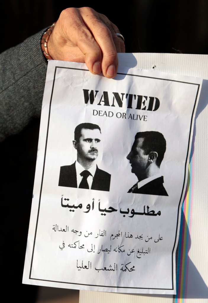 An anti-Syrian regime protester holds a paper showing President Bashar Assad at a sit-in held by Lebanese media advocates in Beirut, Lebanon, on Friday.