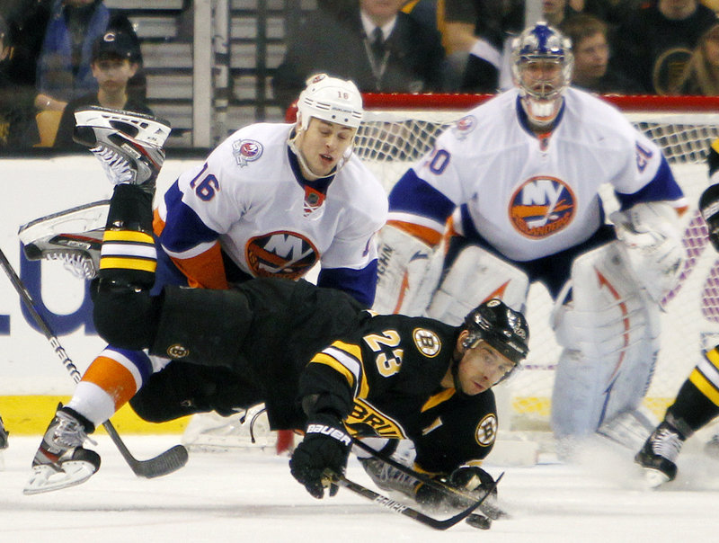 Chris Kelly of the Bruins gets checked to the ice by Marty Reasoner of the Islanders in Saturday’s game at Boston. The Islanders won 3-2, ending a five-game road winless streak.