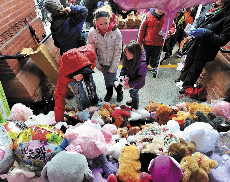 Ashley-Ann Ferris, left, places a teddy bear on the steps of the Waterville City Hall with her cousin Skylar Starbird, 12, center, and daughter Hailie Hotham, 7, during a vigil for missing toddler Ayla Reynolds on Saturday.