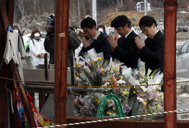A group of men offers prayers in Minamisanriku, Japan, on Sunday. A year after the devastating earthquake and tsunami struck, much work needs to be done.