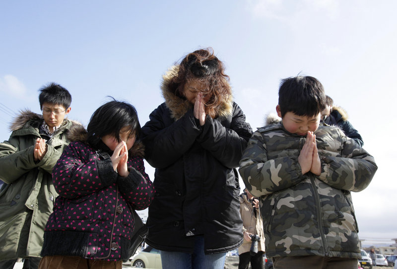A Japanese family observes a moment of silence in front of what is left of a disaster control center in an area devastated by the March 11, 2011 earthquake and tsunami in Minamisanriku, Japan, on Sunday.