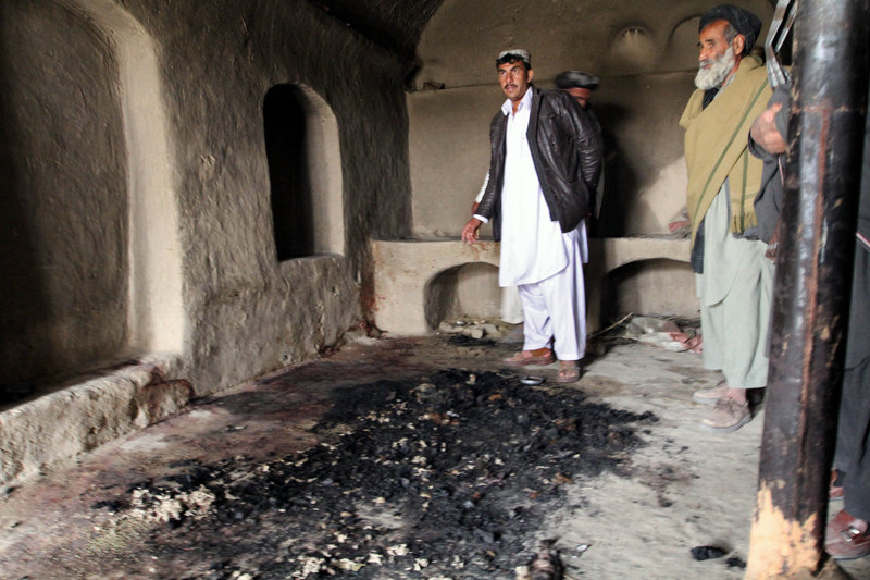 Men stand next to bloodstains and charred remains inside a home where witnesses say Afghans were killed Sunday by a U.S. soldier in Panjwai, Kandahar province. An Afghan youth Monday recounted the terrifying scene in his home as the lone U.S. soldier moved stealthily through it during a killing rampage. The soldier is accused of killing 16 civilians in their homes.