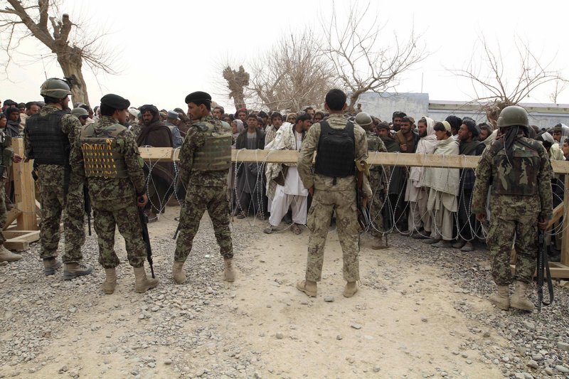 Afghan army soldiers stand guard as a crowd gathers outside a military base in Panjwai, Afghanistan, on Sunday.