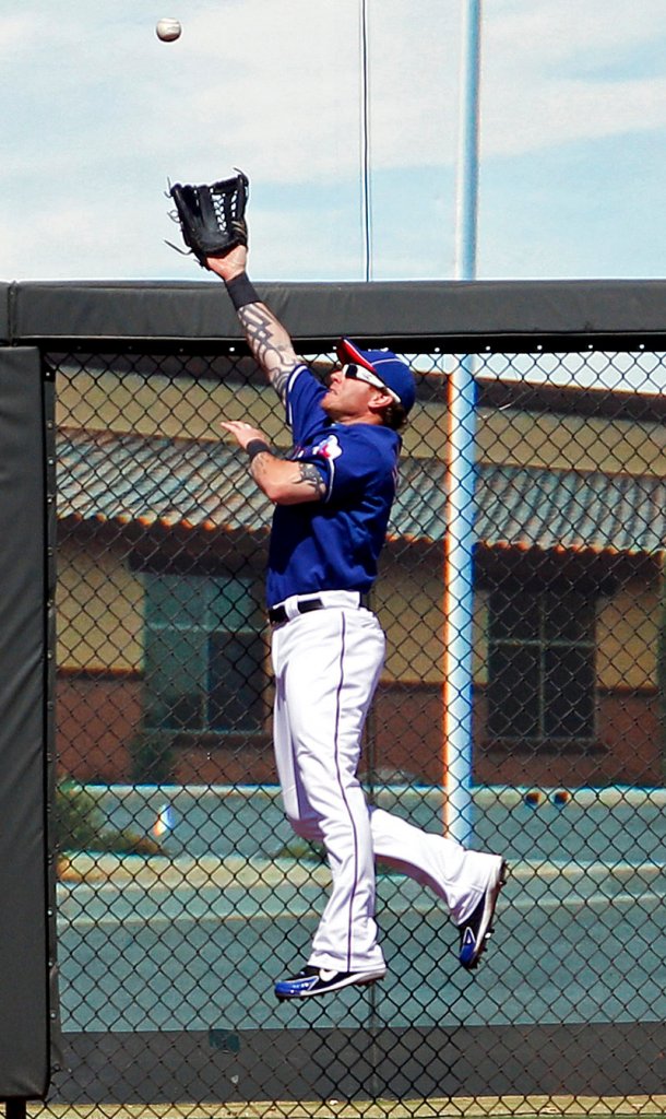 Josh Hamilton of the Rangers leaps against the fence in left field to catch a ball hit by Colorado’s Marco Scutaro. Hamilton later left the game after jamming his right heel.
