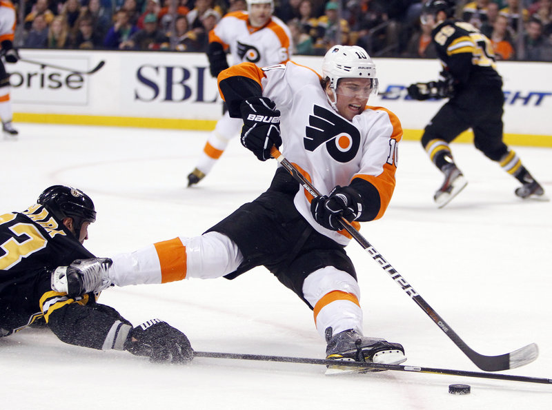 Brayden Schenn of the Flyers gets tripped up by Boston’s Zdeno Chara in Saturday’s game at Boston. The Bruins blew a 2-0 goal lead but came back to win 3-2 in a shootout, halting a four-game skid.