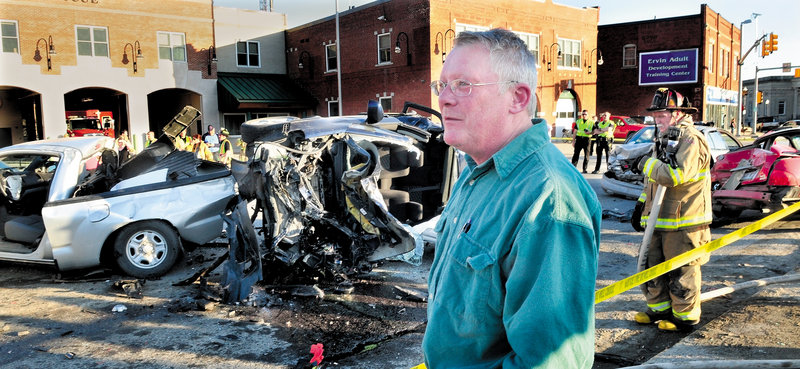 Bob Woodsome of Fairfield talks about the six-vehicle crash that occurred when the Suzuki, behind him, slammed into vehicles at a traffic light at College Avenue and Main Street in Waterville on Sunday. A truck at left and two cars at right were struck. Waterville firefighter Marshal King monitors the scene.