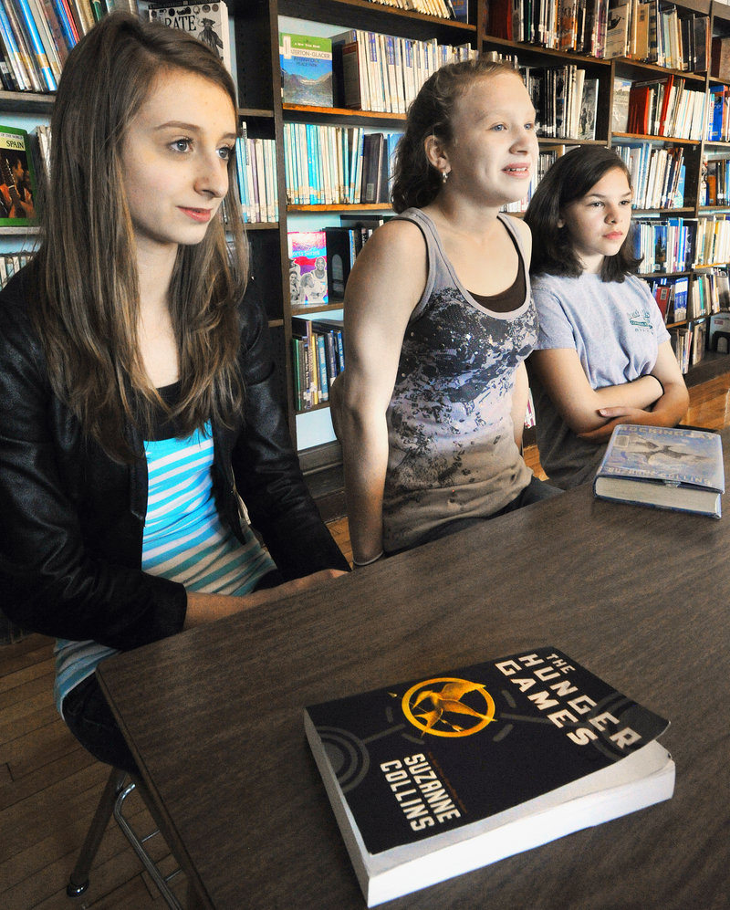 Edita Isakovic, Madison Houlette and Maggie Koukos, eighth-graders at South Portland’s Mahoney Middle School, discuss the popular novel “The Hunger Games.” About 120 Mahoney students will take a field trip to see the movie on Friday.