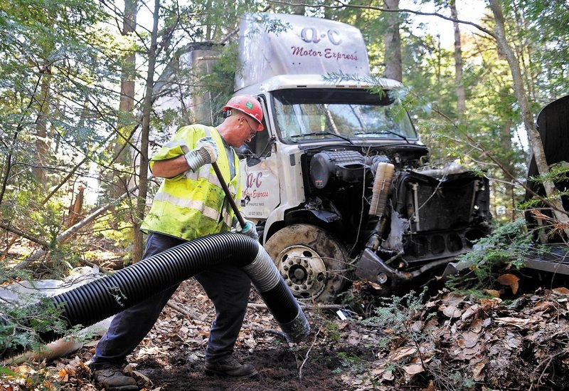Clean Harbors employee Keith Wilson vacuums fuel that spilled Wednesday when a tractor trailer carrying 20 tons of butter crashed off Interstate 295 in Bowdoinham.