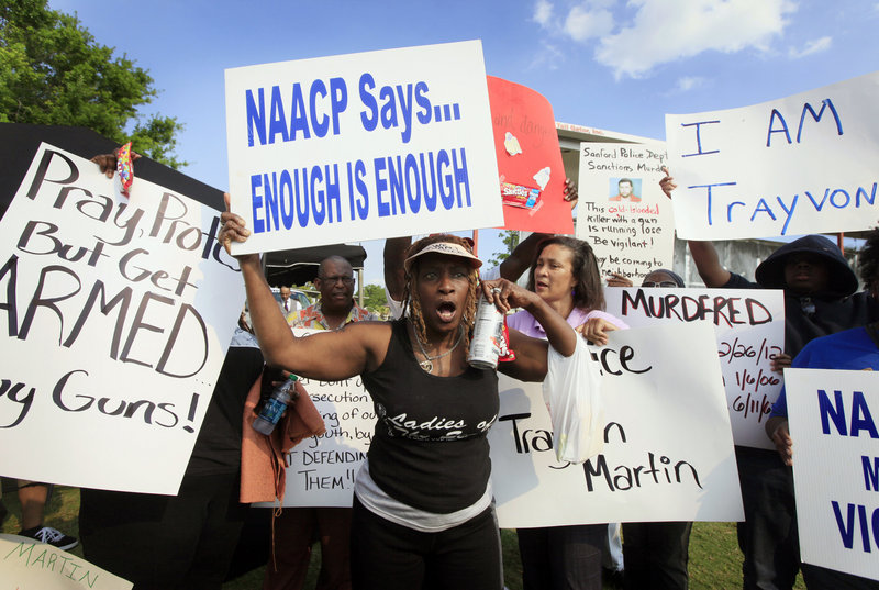 Protester Rene Panko of Tampa, center, and others gather early for a Thursday evening rally for 17-year-old Trayvon Martin, the unarmed black teenager who was fatally shot by a neighborhood watch captain, at Fort Mellon Park in Sanford, Fla.
