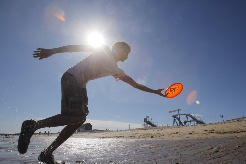 Matthew Laforest of Old Orchard Beach reaches to catch a frisbee while throwing it at Old Orchard Beach with his friend Josh Baumann during Friday’s warm and breezy weather.