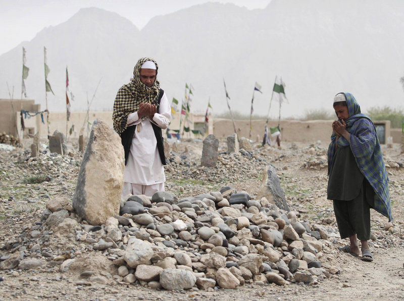 Afghanis pray over the grave of one of the shooting rampage victims on Saturday in the Panjwai district of Kandahar. Families of the dead have said seeing the killer punished is more important than financial compensation.