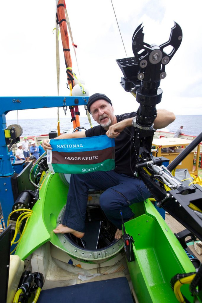 James Cameron holds the National Geographic Society flag after he successfully completed a solo dive to the Mariana Trench. National Geographic was one sponsor of the expedition. Cameron said his super-strong sub shrank three inches under the intense water pressure.