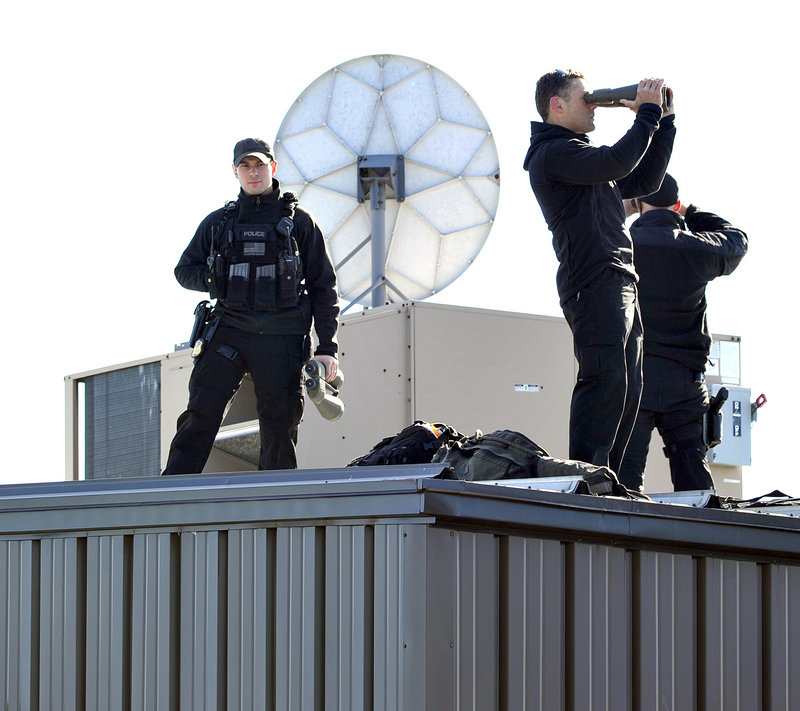 Sharpshooters scan the area from the rooftop as the president’s plane lands at the Portland International Jetport.