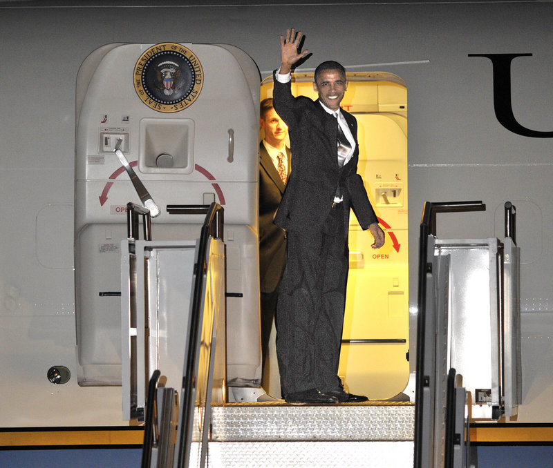 Late Friday, President Obama waves as he boards Air Force One to depart from the Portland International Jetport.