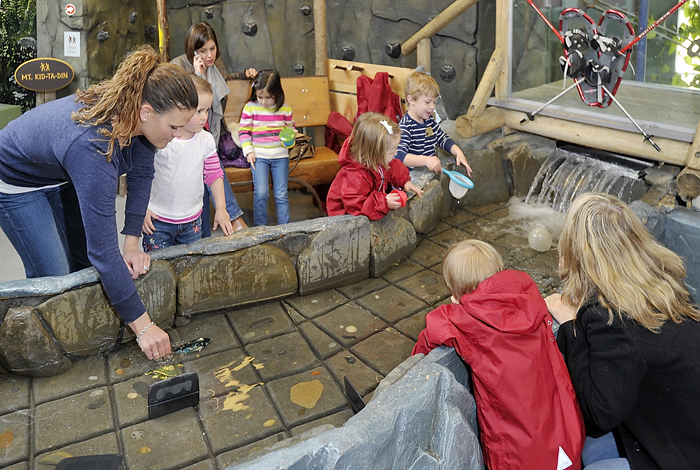 Susan McLain of Portland, left, encourages her daughter, Morgan, 3, to join the other kids in the activities around "The Stream," part of Discovery Woods at the Children's Museum and Theatre of Maine.