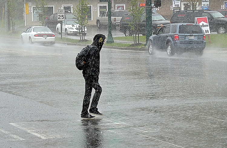 A pedestrian takes it in stride as a heavy downpour at the intersection of Stroudwater and Wayside Drive doesn't deter his casual walk across the Westbrook bypass.