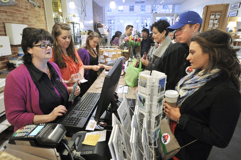 A “cash-mob” swarms Lisa-Marie’s Made in Maine on Exchange Street in Portland on Thursday evening. Shop owner Lisa-Marie Stewart, left, rings up a sale.