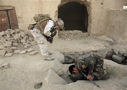A member of U.S. special operations forces and an Afghan National Army soldier search for roadside bombs during a joint patrol in Shewan, a former Taliban stronghold in Afghanistan's Farah province.