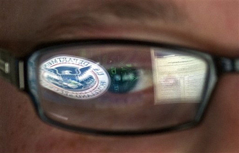 This Sept. 30, 2011 file photo shows a reflection of the Department of Homeland Security logo in the eyeglasses of a cybersecurity analyst at the watch and warning center of the Department of Homeland Security's secretive cyber defense facility in Idaho Falls, Idaho. The center is tasked with protecting the nation's power, water and chemical plants, electrical grid and other facilities from cyber attacks. (AP Photo/Mark J. Terrill, File)