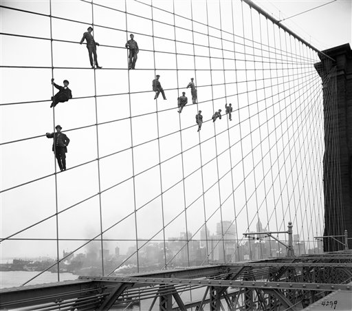 In this Oct. 7, 1914, photo, painters are suspended from wires on the Brooklyn Bridge in New York.