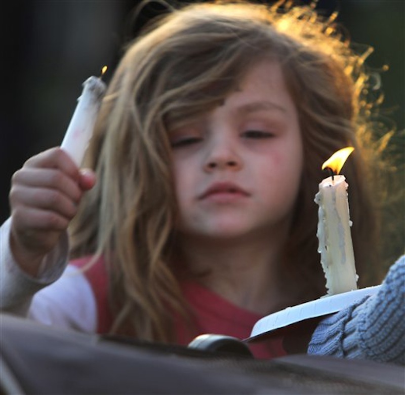 Addie Delisle lights her candle during a vigil for slain Police chief Michael Maloney, Friday, April 13, 2012 in Greenland, N.H. Maloney was trying to serve a search warrant Thursday night when a suspect opened fire, killing the 48-year-old chief, injuring four officers from other departments, and plunging the southeastern New Hampshire community of Greenland into a grief that residents say they won't soon get over. (AP Photo/Jim Cole)