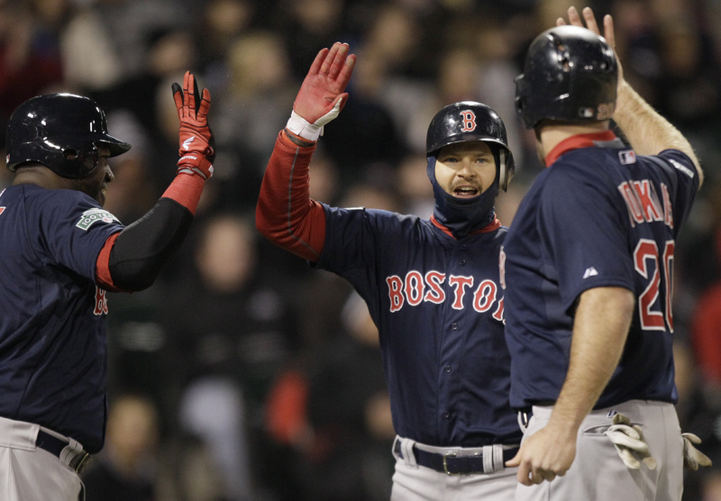 Cody Ross, center, celebrates with Kevin Youkilis, right, and David Ortiz after scoring on a three-run double by Darnell McDonald in the sixth inning of the Boston Red Sox game against the Chicago White Sox in Chicago on Friday.