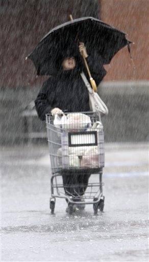 A shopper braves heavy rain while leaving a grocery store in Brunswick today.