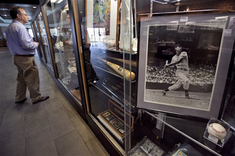 Baseball fan Sumner Friedstein, of West Newbury, Mass., left, views items once owned by Boston Red Sox's Ted Williams near a photograph of Williams from the 1942 season, right, in a display case at Fenway Park during an auction preview, Wednesday, April 25, 2012, in Boston. (AP Photo/Steven Senne)