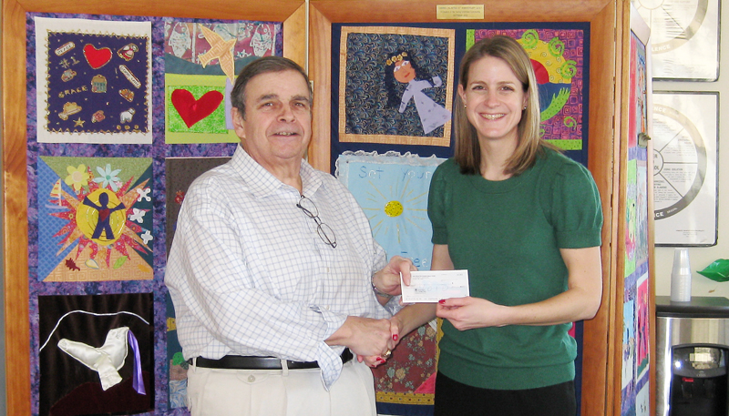 Roger Lachance, a member of the board of directors for Beacon Charitable Corporation, hands a check to Emily Flowers, public awareness and community support coordinator at Caring Unlimited.