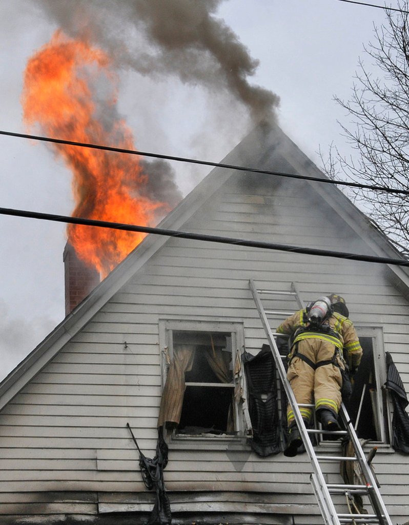 A firefighter climbs a ladder to reach the fire at 28 Raymond St. in Biddeford on Saturday morning. No one was hurt.