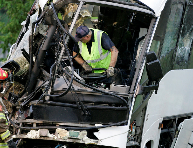 An emergency worker wrestles with the steering wheel of a bus after an Aug. 8, 2008 crash in Sherman, Texas, that killed 17 people. The bus had passed a state inspection eight days before the accident. The owners of the company that had inspected the bus are still in the inspection business.