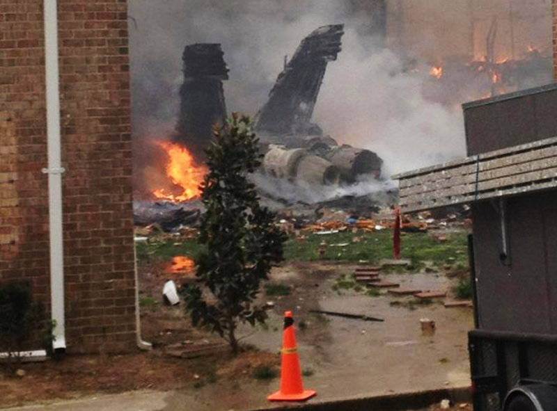 The fuselage of an F/A-18D Hornet lies smoldering after crashing into a residential building in Virginia Beach, Va., on Friday. Two pilots were able to eject from the jet before it crashed, and were treated for injuries that were not life-threatening.