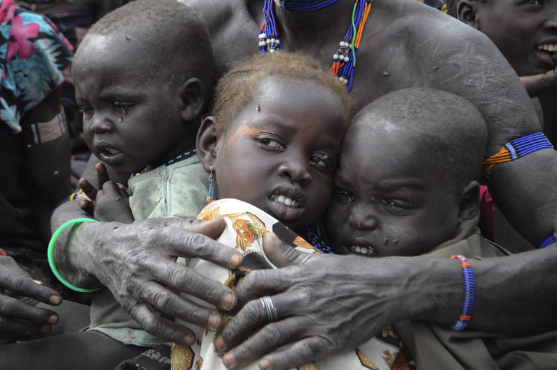 A family waits for emergency food rations after fleeing their home in South Sudan in January. While some people are returning to their homes, others have refused to leave transit sites to return to traditional villages that lack resources.