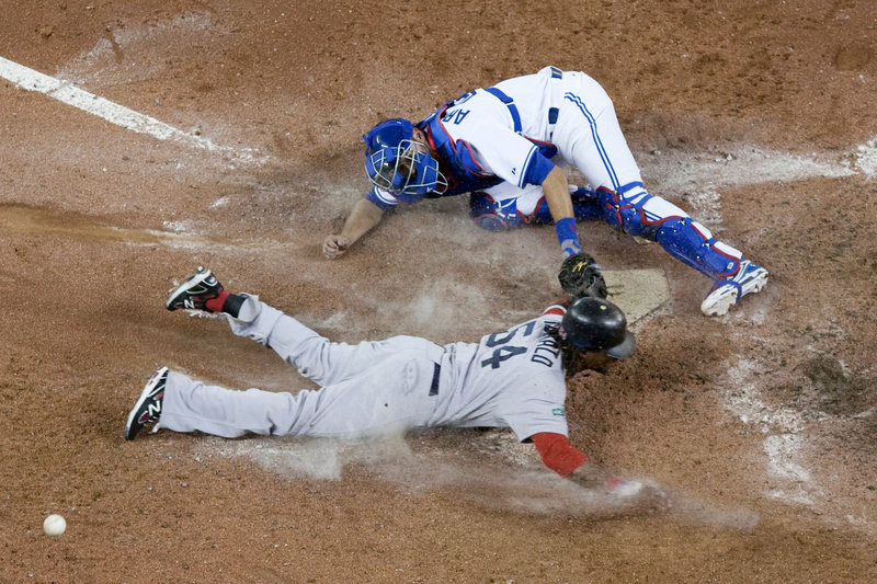 Darnell McDonald, pinch running for David Ortiz, slides into home plate to score the go-ahead run as Blue Jays catcher J.P Arencibia can’t handle the throw in the ninth inning of Monday night’s game in Toronto.