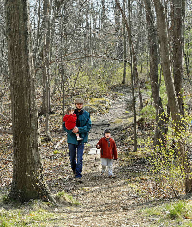 Neighborhood resident Tim Willoughby walks one of the paths in “Canco Woods,” with daughter, Maeve, 2, and son Thomas, 4, on Tuesday. Residents say the wooded area provides recreation for families, but a sale is pending on the 12.75-acre parcel, and it may be developed.