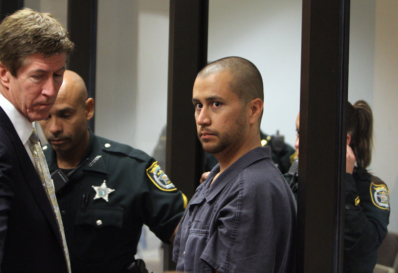 George Zimmerman is directed by a Seminole County deputy and his attorney Mark O’Mara during a court hearing Thursday in Sanford, Fla. Zimmerman has been charged with second-degree murder in the shooting death of 17-year-old Trayvon Martin.